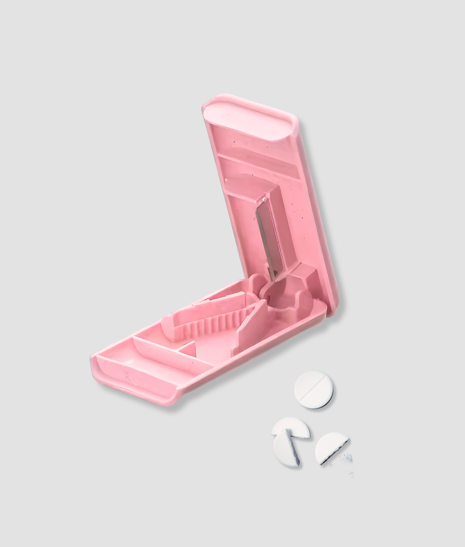 Roze pillensnijder open met witte pillen en halfjes