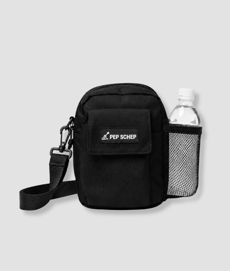 PEP SCHEP Bottle Bag – zwarte schoudertas met PEP SCHEP logo, karabijnhaak, verstelbare riem en zijvak met gaasnet voor een drinkfles