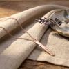 Rosé gouden rechthoekige staafvormige hanger met naam gravure aan rosé gouden ketting liggend op linnen doek met lavendel lifestyle modelfoto gepersonaliseerd rosé gouden naamketting sieraad
