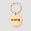 Ronde gouden sleutelhanger met zwarte tekst CUSTOM gravure