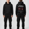 Man in zwarte hoodie met tekst STAY IN THE MOMENT en no-camera iconen op de rug