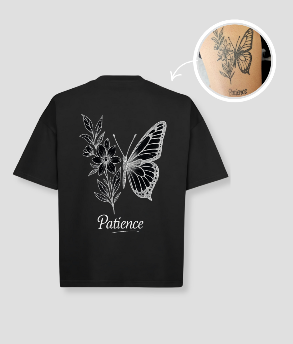 Zwart oversized unisex t-shirt met 'Patience' vlinder en bloemen tattoo opdruk van PEP SCHEP – witte botanische vlinder illustratie op de voorkant