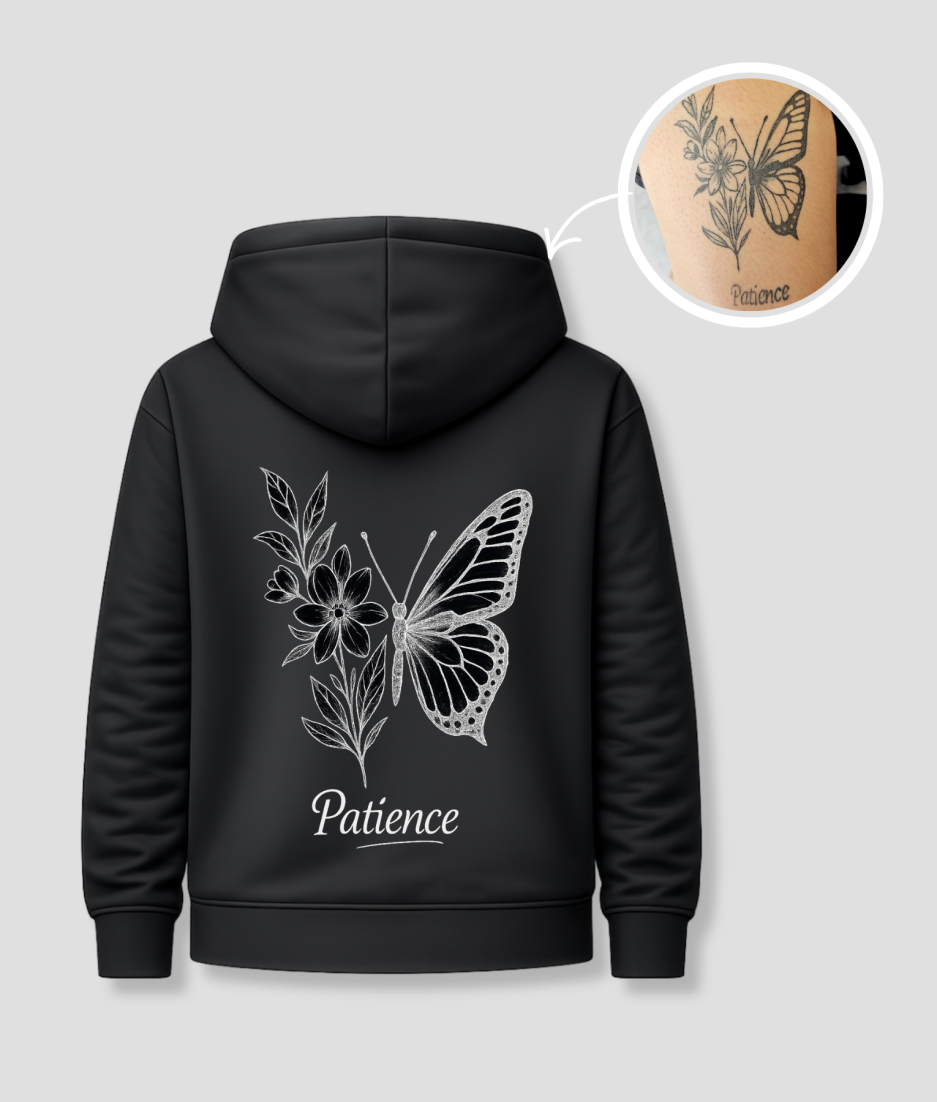 Zwarte unisex hoodie met 'Patience' vlinder en bloemen tattoo opdruk van PEP SCHEP – grote witte rugprint met botanische vlinder illustratie