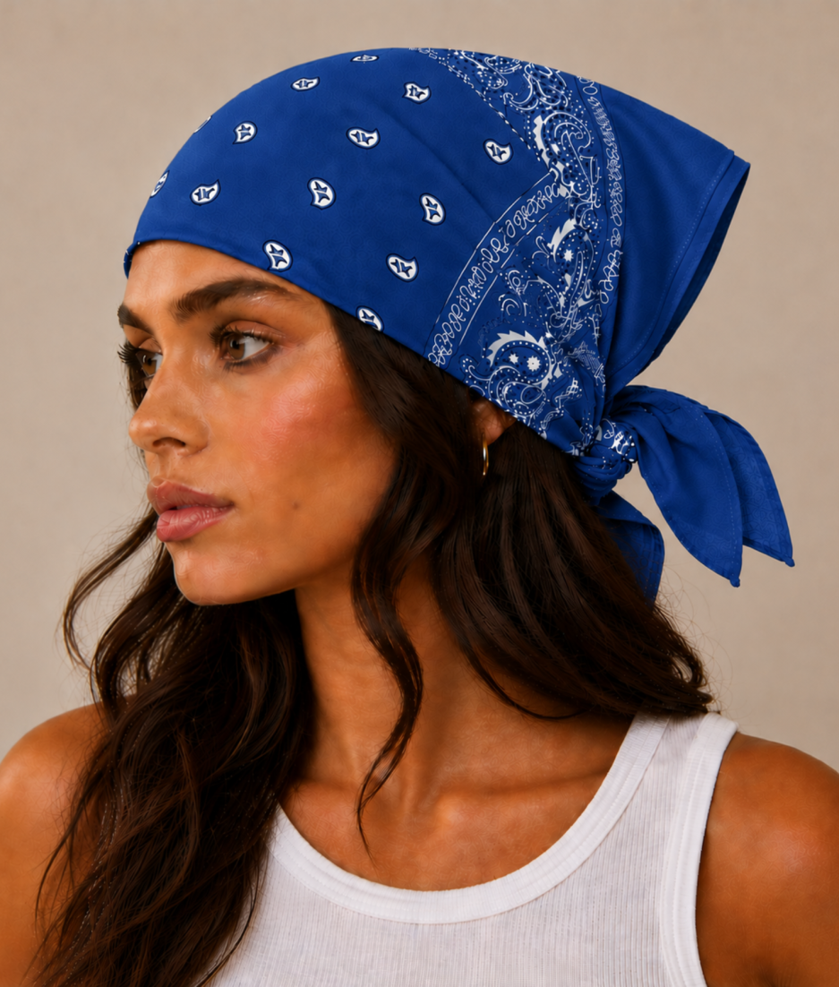Blauwe bandana gedragen door model – klassieke paisley bandana in blauw met witte print, gedragen als hoofddoek. Veelzijdig te stylen als haarband, nekdoek of accessoire. Ideaal als cadeau of festival- en zomeraccessoire.