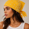 Gele bandana gedragen door model – klassieke paisley bandana in geel met witte print, gedragen als hoofddoek. Veelzijdig te stylen als haarband, nekdoek of accessoire. Ideaal als cadeau of festival- en zomeraccessoire.