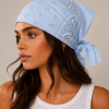 Lichtblauwe bandana gedragen door model – klassieke paisley bandana in lichtblauw met witte print, gedragen als hoofddoek. Veelzijdig te stylen als haarband, nekdoek of accessoire. Ideaal als cadeau of festival- en zomeraccessoire.