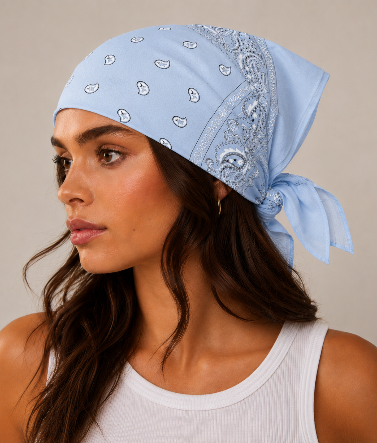 Lichtblauwe bandana gedragen door model – klassieke paisley bandana in lichtblauw met witte print, gedragen als hoofddoek. Veelzijdig te stylen als haarband, nekdoek of accessoire. Ideaal als cadeau of festival- en zomeraccessoire.