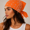 Oranje bandana gedragen door model – klassieke paisley bandana in oranje met witte print, gedragen als hoofddoek. Veelzijdig te stylen als haarband, nekdoek of accessoire. Ideaal als cadeau of festival- en zomeraccessoire.