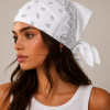 Witte bandana gedragen door model – klassieke paisley bandana in wit met grijze print, gedragen als hoofddoek. Veelzijdig te stylen als haarband, nekdoek of accessoire. Ideaal als cadeau of festival- en zomeraccessoire.