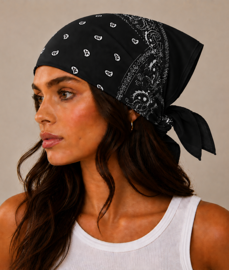 Zwarte bandana gedragen door model – klassieke paisley bandana in zwart met witte print, gedragen als hoofddoek. Veelzijdig te stylen als haarband, nekdoek of accessoire. Ideaal als cadeau of festival- en zomeraccessoire.