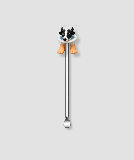 Mini schepje cocktailstirrer met koe figuur met zwart-wit koeienhoofd op wit bord en twee oranje pootjes uit de Italian Brainrot collectie bovenop en zilveren steel