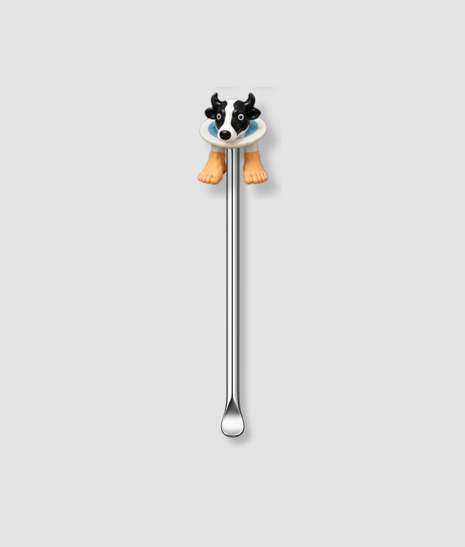 Mini schepje cocktailstirrer met koe figuur met zwart-wit koeienhoofd op wit bord en twee oranje pootjes uit de Italian Brainrot collectie bovenop en zilveren steel