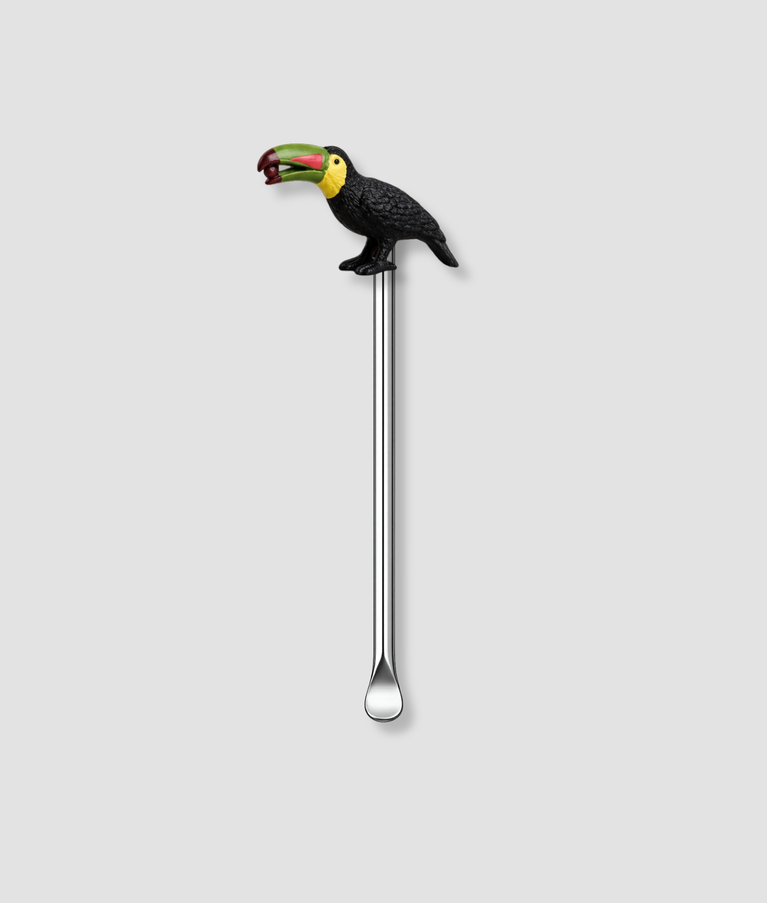 Mini schepje cocktailstirrer met zwarte toekan vogelfiguur bovenop en zilveren steel op lichtgrijze achtergrond