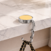 Gouden ronde tassenhanger op marmeren tafel met zwarte handtas