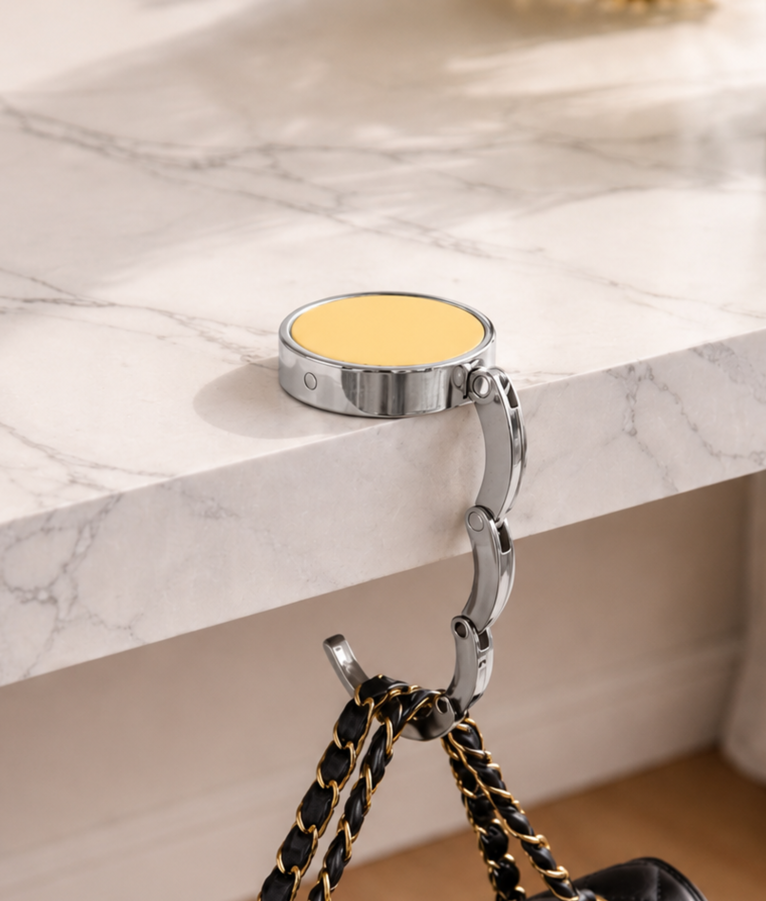 Gouden ronde tassenhanger op marmeren tafel met zwarte handtas
