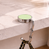 Groene ronde tassenhanger op marmeren tafel met zwarte handtas