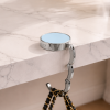 Lichtblauwe opvouwbare tassenhanger aan tafel met handtas