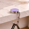 Lila opvouwbare tassenhanger aan tafel met handtas