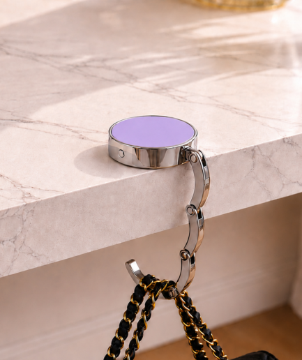 Lila opvouwbare tassenhanger aan tafel met handtas