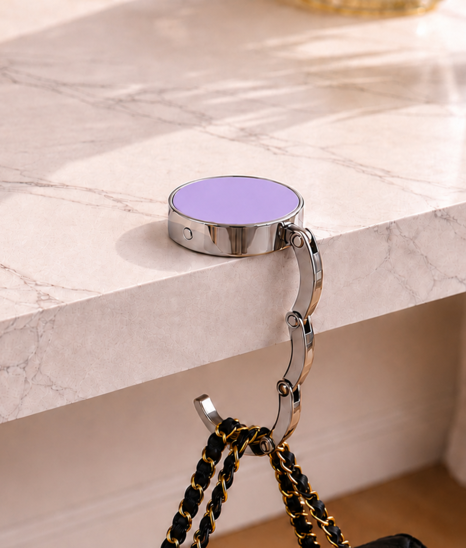 Lila opvouwbare tassenhanger aan tafel met handtas