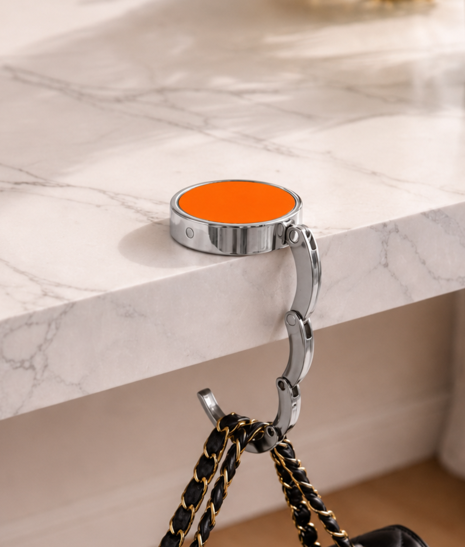 Oranje opvouwbare tassenhanger aan tafel met handtas