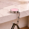 Roze opvouwbare tassenhanger aan tafel met handtas