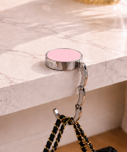 Roze opvouwbare tassenhanger aan tafel met handtas