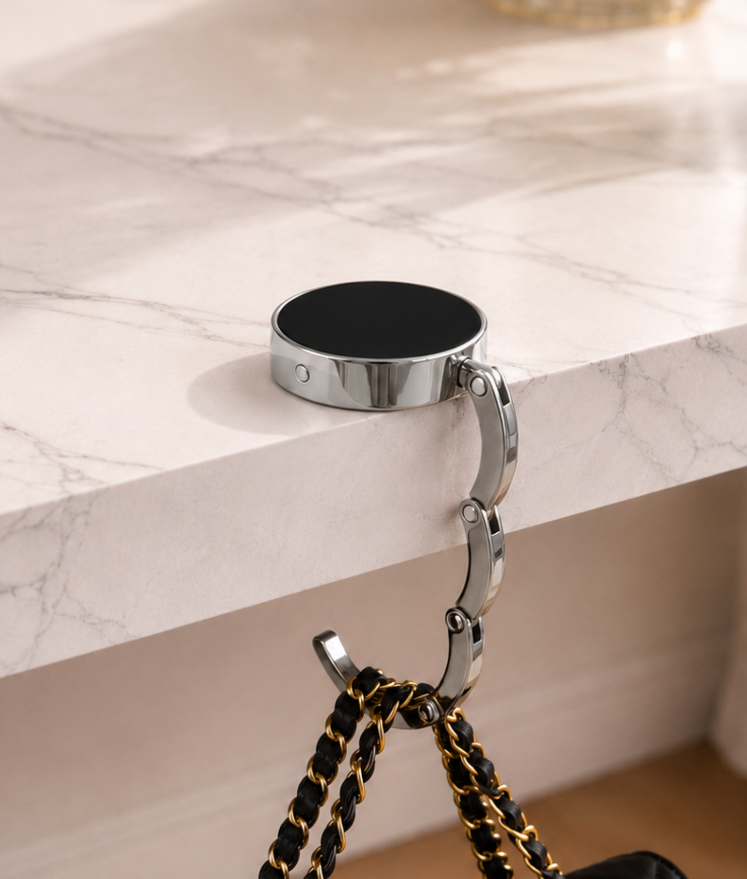 Zwarte opvouwbare tassenhanger aan tafel met handtas