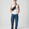 Man met zwarte crossbody fanny pack met flesje, wit tanktopje en zwarte pet