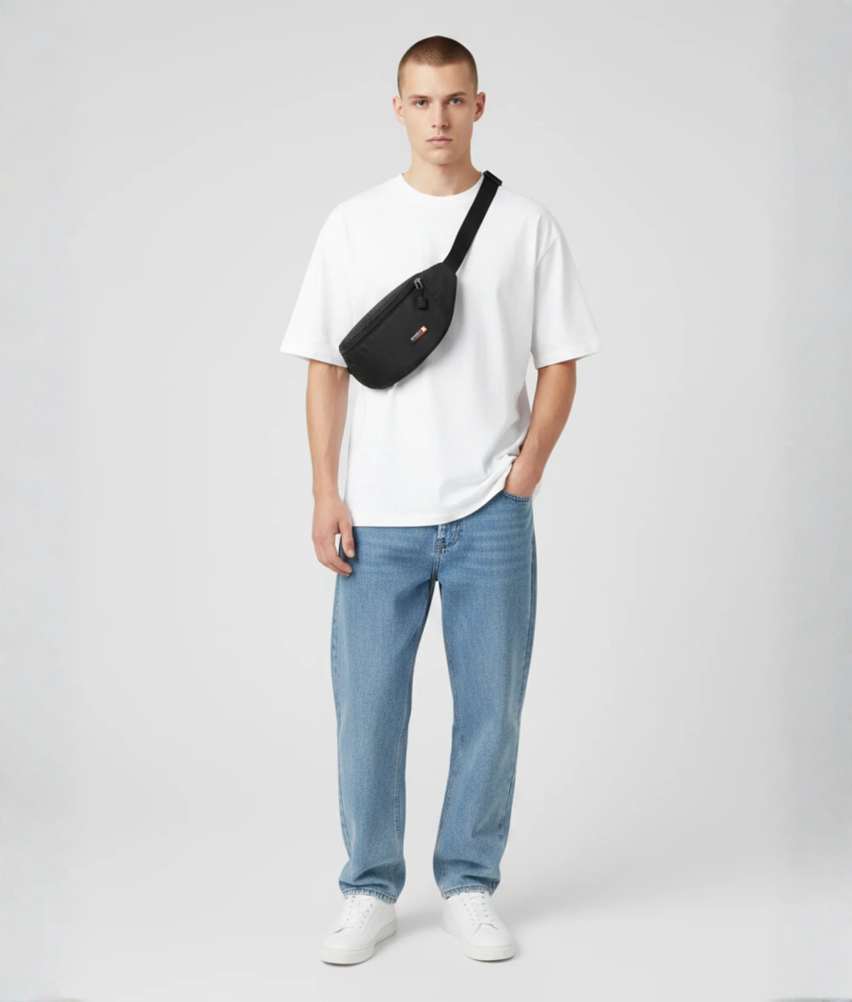 Man met zwarte crossbody fanny pack over wit oversized T-shirt en blauwe jeans