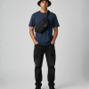 Man met zwarte bucket hat en zwarte crossbody fanny pack over blauw T-shirt