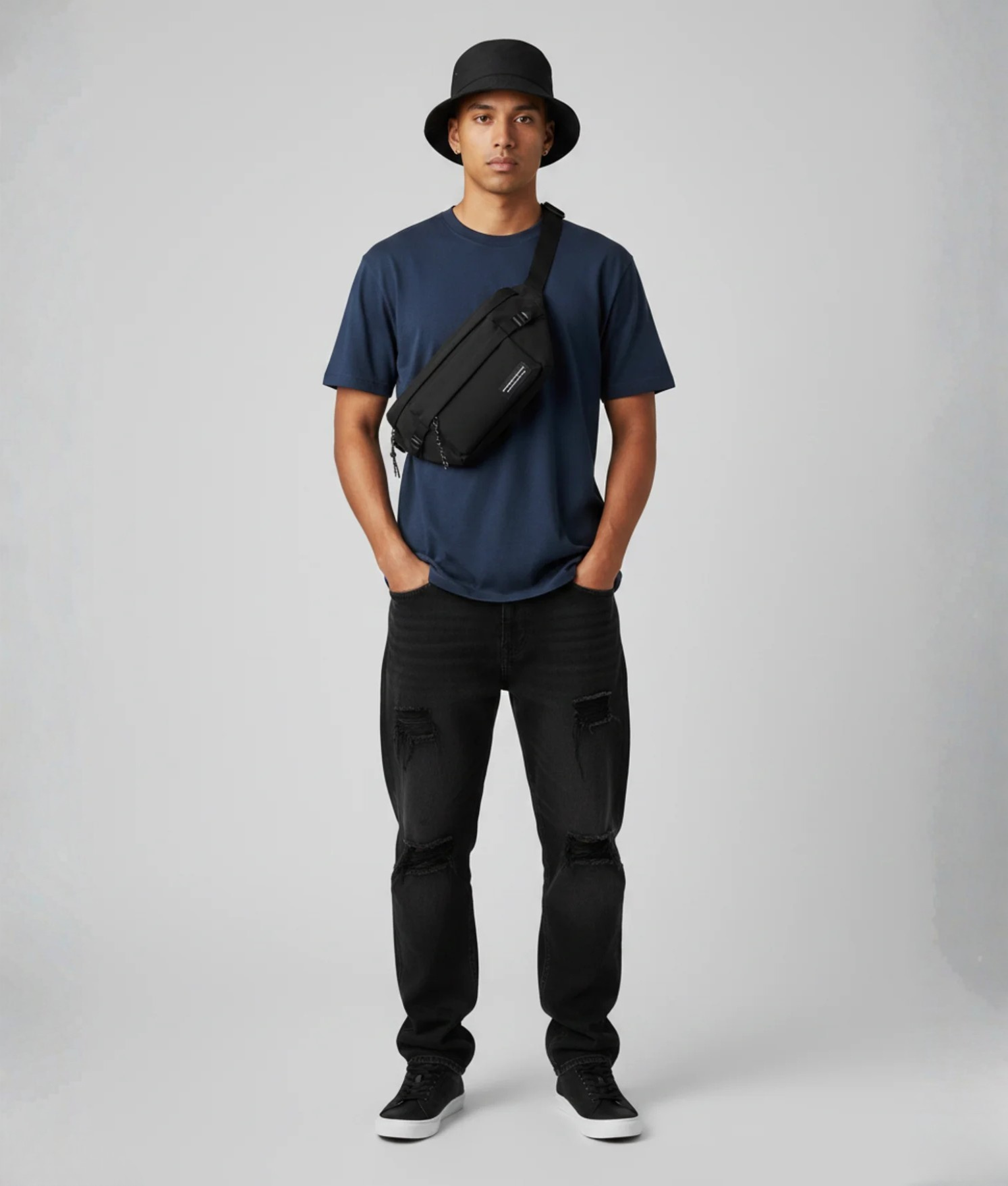 Man met zwarte bucket hat en zwarte crossbody fanny pack over blauw T-shirt