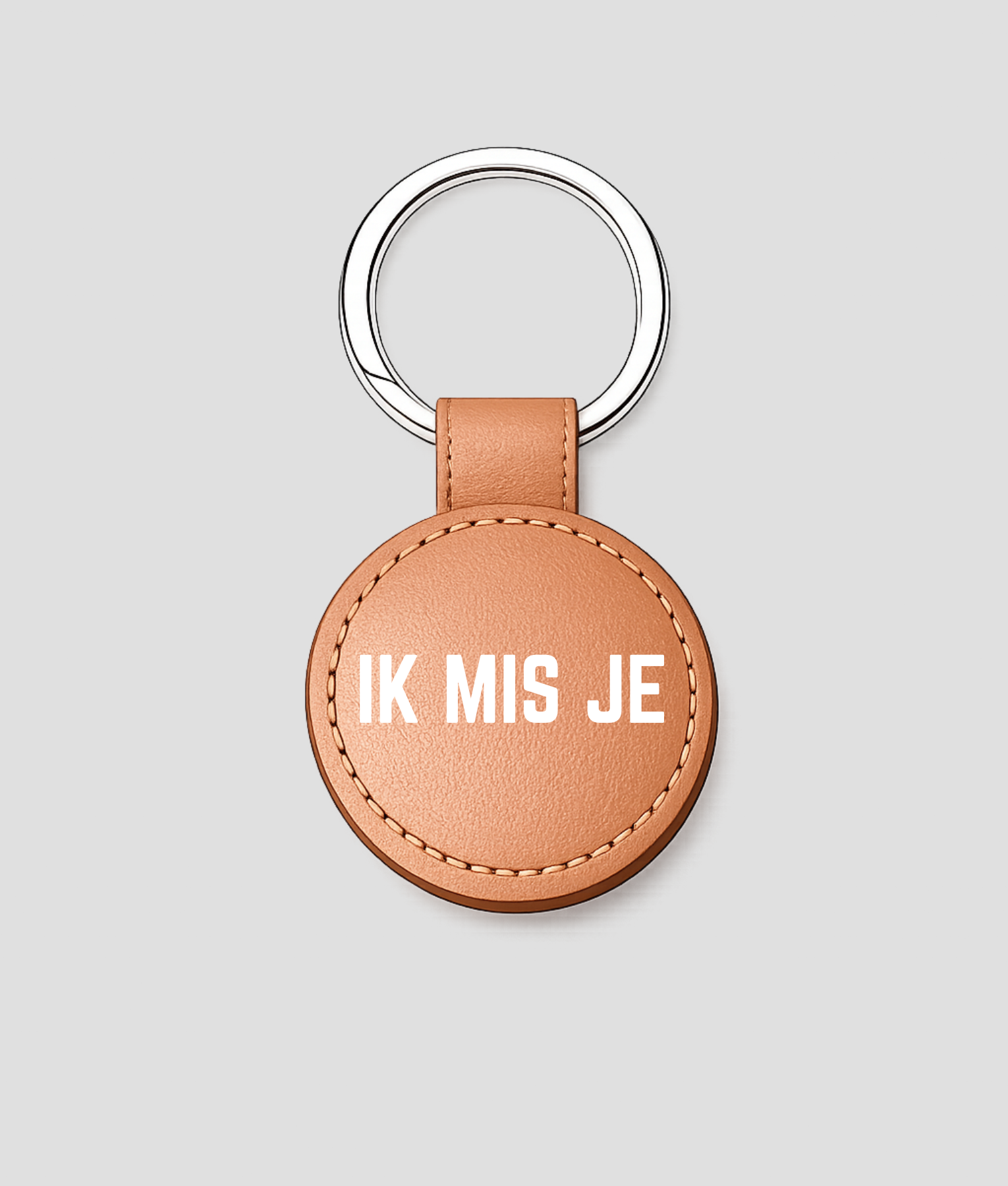 Koperkleurige ronde leren sleutelhanger met zilveren ring en tekst 'IK MIS JE'