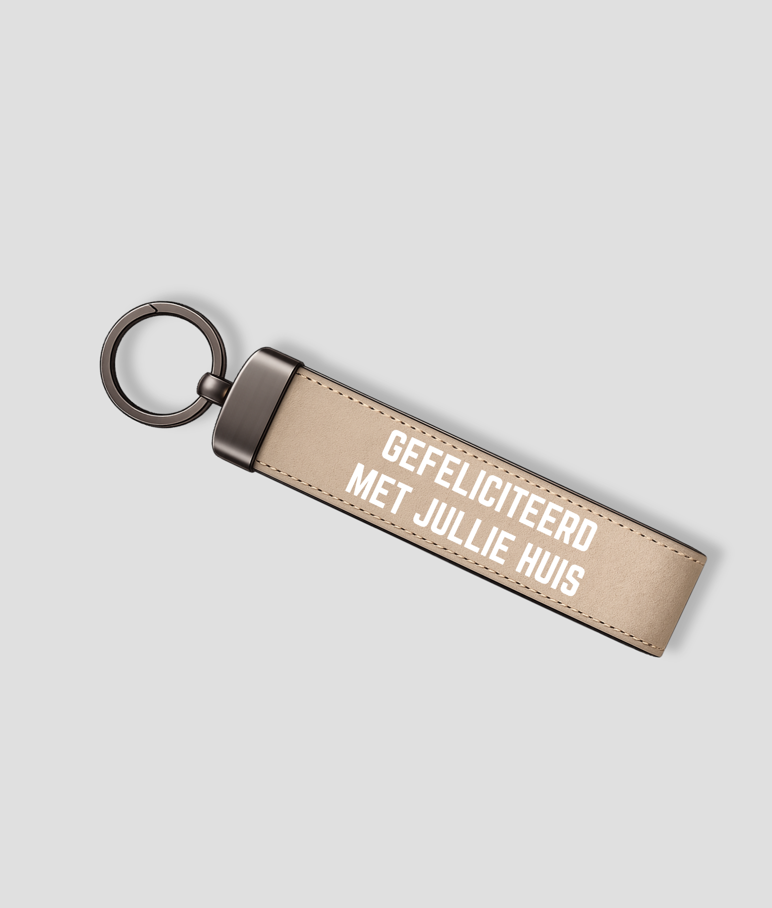 Zandkleurige suède sleutelhanger met metalen ring en tekst 'GEFELICITEERD MET JULLIE HUIS'