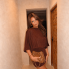 Model draagt cognac bruine leren festivaltas met gouden kettingband